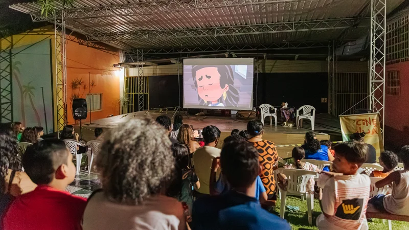 Cine Juá: cineclube itinerante promove oficina com bolsas para jovens no sertão de Aguiar 2 Noite de exibição do Cine Juá, com telão de cinema ao fundo e crianças no primeiro plano